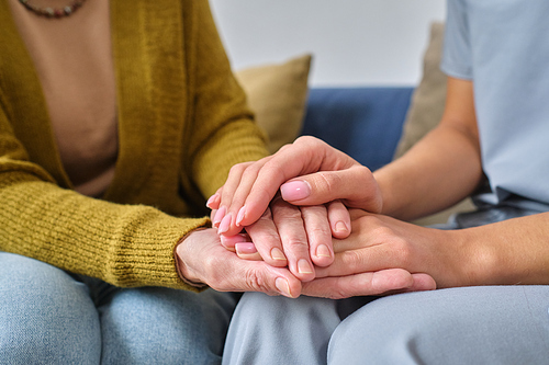 Close-up of nurse holding hands of senior woman, she supporting and caring about her during disease