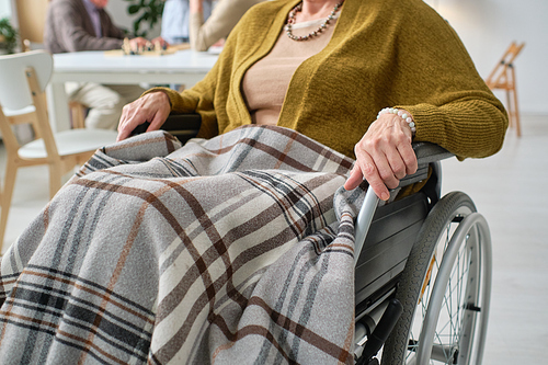 Close-up of senior woman with disability sitting in wheelchair under the blanket at hospital