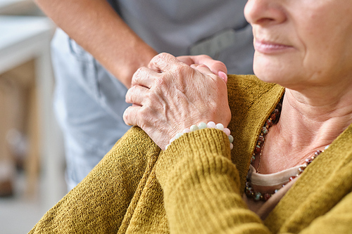 Close-up of elderly woman holding the hand of the nurse, she feeling the support from her