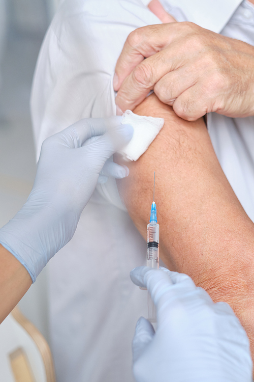 Close-up of patient getting an injection in his arm by the nurse during medical procedure