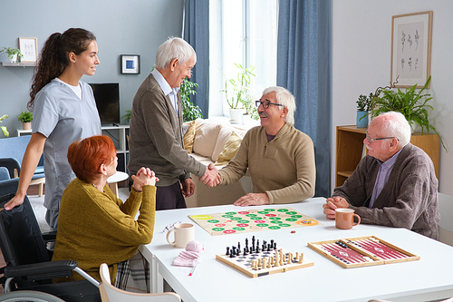 Senior man greeting his friends in the room, they gathering to play board games together