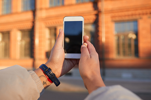 Close-up of woman holding mobile phone and photographing the building outdoors in the city