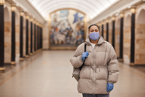 Portrait of woman in warm clothing and in protective wear looking at camera while walking in pandemic