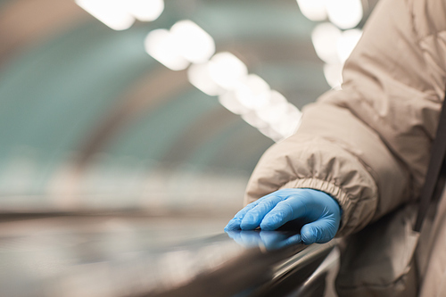 Close-up of woman in protective gloves standing on escalator in underground