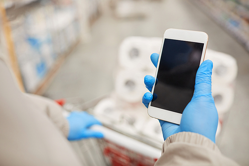 Close-up of woman looking at the screen of her mobile phone while doing shopping