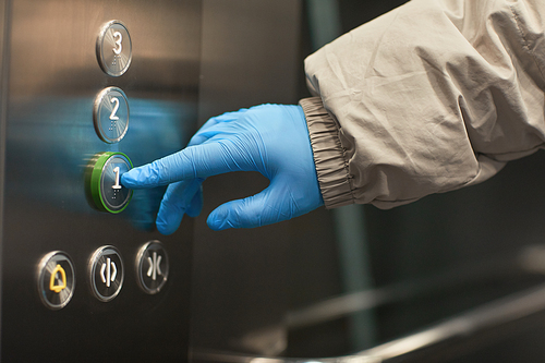 Close-up of woman in protective gloves pushing the button in elevator