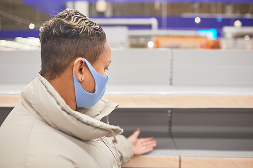 Rear view of woman in short hair and in protective mask standing in the mall