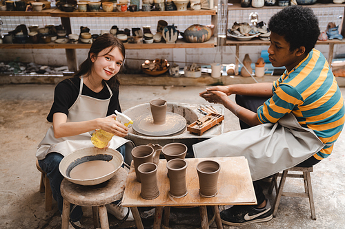 happy smiling girl having fun to learning and work with craft art of clay hand-made workshop in ceramic studio, little ceramist enjoy in creative handcraft hobby with pottery artisan school class