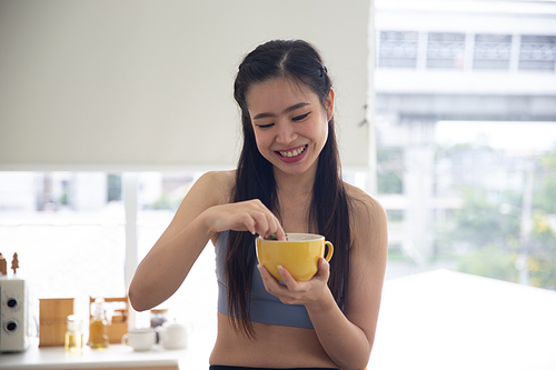 young Asian woman cooking vegetable healthy food and eating or drinking in home kitchen