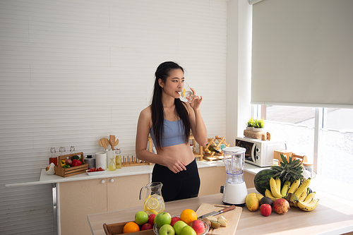 young Asian woman cooking vegetable healthy food and eating or drinking in home kitchen