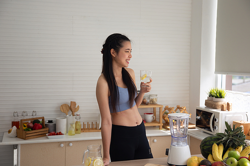 young Asian woman cooking vegetable healthy food and eating or drinking in home kitchen