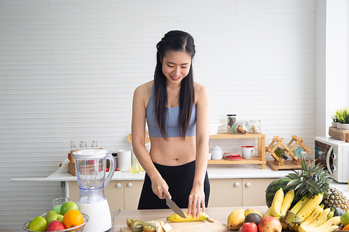 young Asian woman cooking vegetable healthy food and eating or drinking in home kitchen