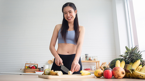 young Asian woman cooking vegetable healthy food and eating or drinking in home kitchen