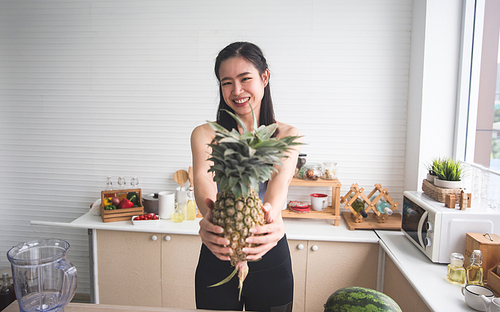 young Asian woman cooking vegetable healthy food and eating or drinking in home kitchen