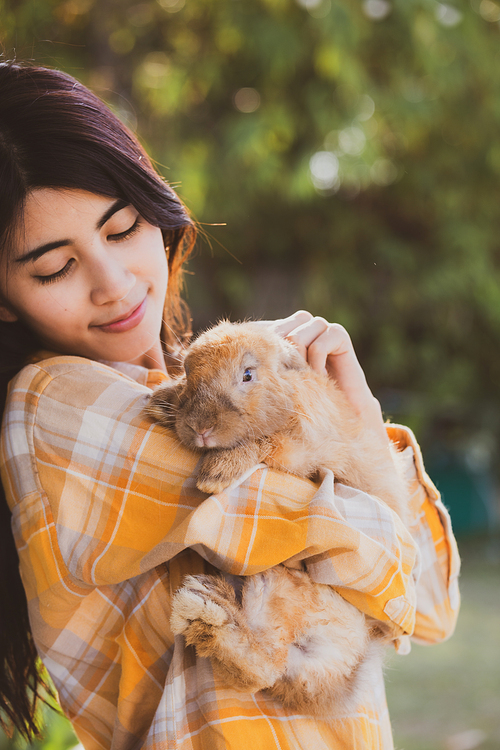 beautiful pretty portrait of young Asian woman person with cute rabbit in pet and animal care concept, happy female holding bunny at nature outdoor field with friendship, easter concept