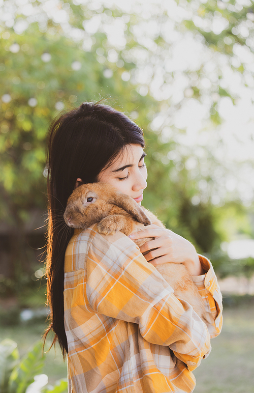 beautiful pretty portrait of young Asian woman person with cute rabbit in pet and animal care concept, happy female holding bunny at nature outdoor field with friendship, easter concept