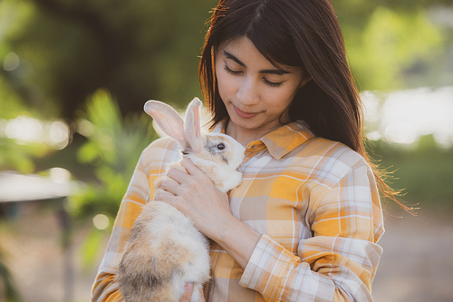 beautiful pretty portrait of young Asian woman person with cute rabbit in pet and animal care concept, happy female holding bunny at nature outdoor field with friendship, easter concept