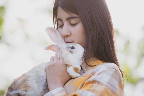 beautiful pretty portrait of young Asian woman person with cute rabbit in pet and animal care concept, happy female holding bunny at nature outdoor field with friendship, easter concept