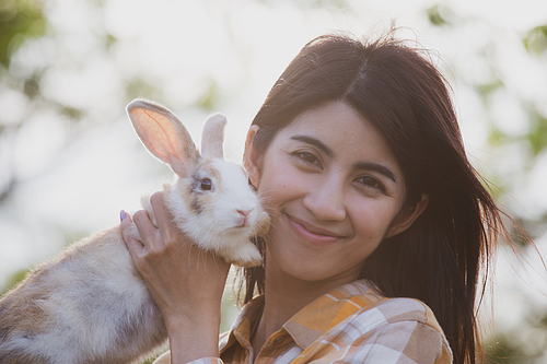 relationships of cheerful rabbit and happy young human girl, Asian woman holding and carrying cute rabbit with tenderness and love. Friendship with cute easter bunny. Happy of Easter's Day