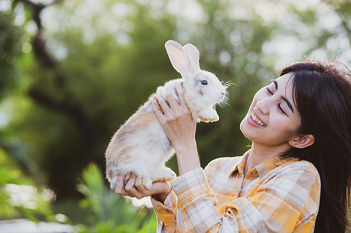 relationships of cheerful rabbit and happy young human girl, Asian woman holding and carrying cute rabbit with tenderness and love. Friendship with cute easter bunny. Happy of Easter's Day