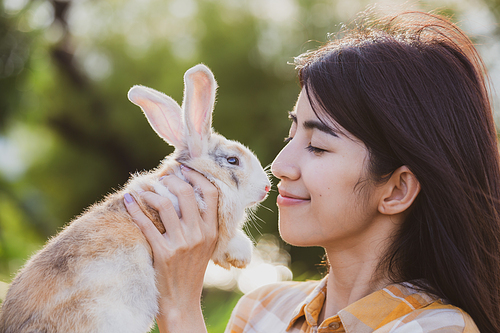 relationships of cheerful rabbit and happy young human girl, Asian woman holding and carrying cute rabbit with tenderness and love. Friendship with cute easter bunny. Happy of Easter's Day