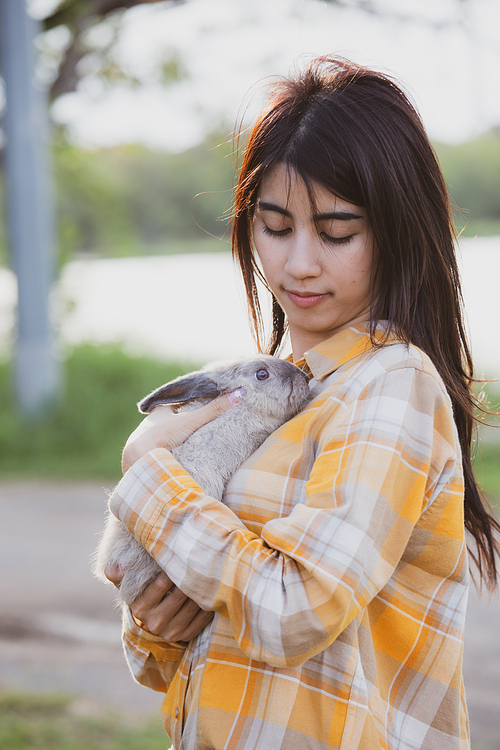 relationships of cheerful rabbit and happy young human girl, Asian woman holding and carrying cute rabbit with tenderness and love. Friendship with cute easter bunny. Happy of Easter's Day