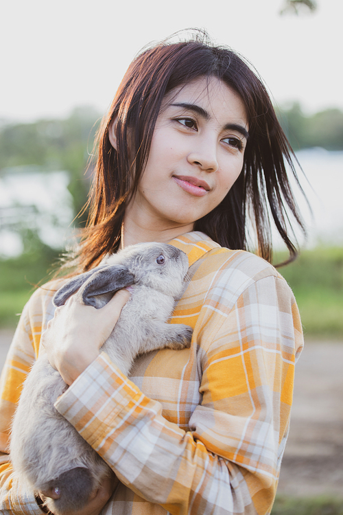 relationships of cheerful rabbit and happy young human girl, Asian woman holding and carrying cute rabbit with tenderness and love. Friendship with cute easter bunny. Happy of Easter's Day