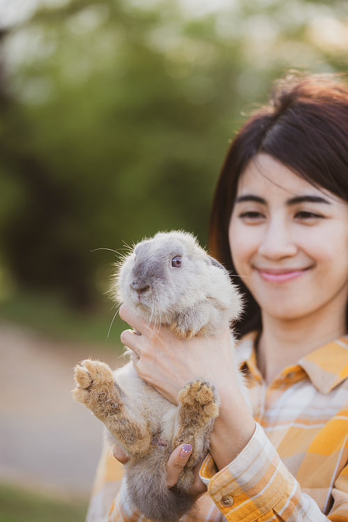 relationships of cheerful rabbit and happy young human girl, Asian woman holding and carrying cute rabbit with tenderness and love. Friendship with cute easter bunny. Happy of Easter's Day