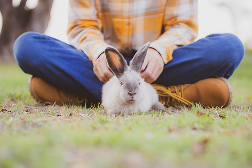 beautiful pretty portrait of young Asian woman person with cute rabbit in pet and animal care concept, happy female holding bunny at nature outdoor field with friendship, easter concept