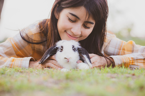 beautiful pretty portrait of young Asian woman person with cute rabbit in pet and animal care concept, happy female holding bunny at nature outdoor field with friendship, easter concept