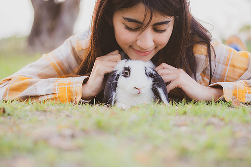 relationships of cheerful rabbit and happy young human girl, domestic friendship family of little cute easter pet and friends person having smile and fun, animal love and care at home concept