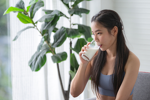 young beautiful woman person are drinking a fresh milk for body health care, smile girl holding glass of milk by happy attractive lifestyle at home, dairy breakfast product having calcium