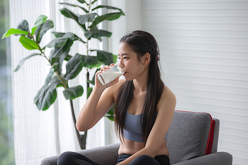 young beautiful woman person are drinking a fresh milk for body health care, smile girl holding glass of milk by happy attractive lifestyle at home, dairy breakfast product having calcium