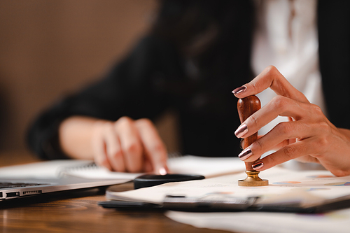 Person's hand stamping with approved stamp on certificate document public paper agreements at desk of notary or business people work, businesswoman making a signs permit on paper work business success