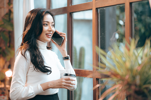 freelance business woman using smartphone or mobile phone to work on online communication technology, young Asian businesswoman or female entrepreneur with laptop computer to working on cyberspace