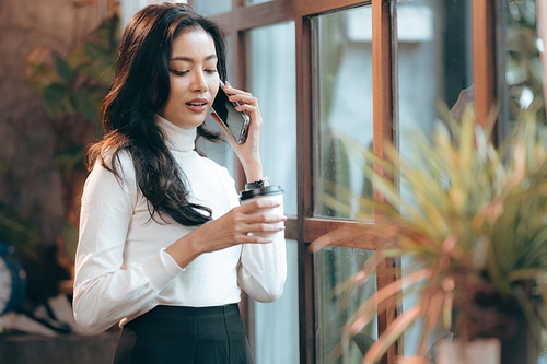 freelance business woman using smartphone or mobile phone to work on online communication technology, young Asian businesswoman or female entrepreneur with laptop computer to working on cyberspace