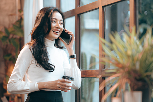 freelance business woman using smartphone or mobile phone to work on online communication technology, young Asian businesswoman or female entrepreneur with laptop computer to working on cyberspace