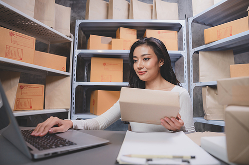 woman entrepreneur's hand holding package of parcel box, Preparing pack delivery packet product for selling online of home shipping service, Startup with small business marketing concept