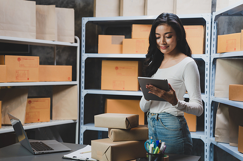 young beautiful woman smiling and happy with thumbs up handle the parcel. Young women packing a parcel order for shipping service to online customer.