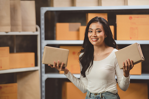 woman entrepreneur's hand holding package of parcel box, Preparing pack delivery packet product for selling online of home shipping service, Startup with small business marketing concept