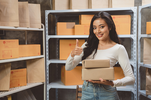 woman entrepreneur's hand holding package of parcel box, Preparing pack delivery packet product for selling online of home shipping service, Startup with small business marketing concept