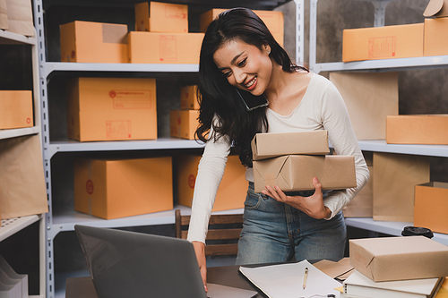 young beautiful woman smiling and happy with thumbs up handle the parcel. Young women packing a parcel order for shipping service to online customer.