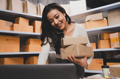 young beautiful woman smiling and happy with thumbs up handle the parcel. Young women packing a parcel order for shipping service to online customer.