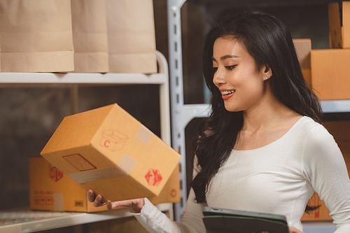 young beautiful woman smiling and happy with thumbs up handle the parcel. Young women packing a parcel order for shipping service to online customer.