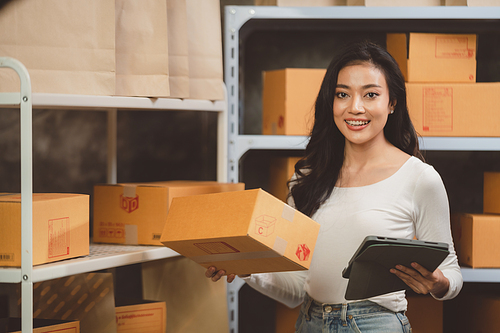 young beautiful woman smiling and happy with thumbs up handle the parcel. Young women packing a parcel order for shipping service to online customer.