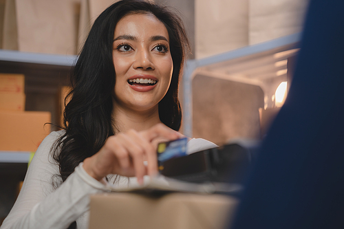 credit card and wireless POS terminal for card payment concept, Young Asian girl with a credit card received a parcel from a male delivery man The woman paid the male delivery man