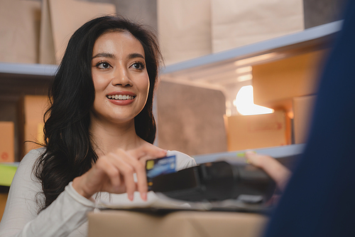 credit card and wireless POS terminal for card payment concept, Young Asian girl with a credit card received a parcel from a male delivery man The woman paid the male delivery man