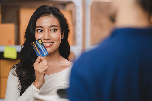 credit card and wireless POS terminal for card payment concept, Young Asian girl with a credit card received a parcel from a male delivery man The woman paid the male delivery man