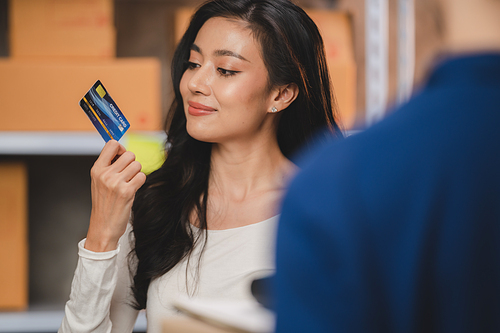 credit card and wireless POS terminal for card payment concept, Young Asian girl with a credit card received a parcel from a male delivery man The woman paid the male delivery man