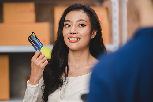 credit card and wireless POS terminal for card payment concept, Young Asian girl with a credit card received a parcel from a male delivery man The woman paid the male delivery man